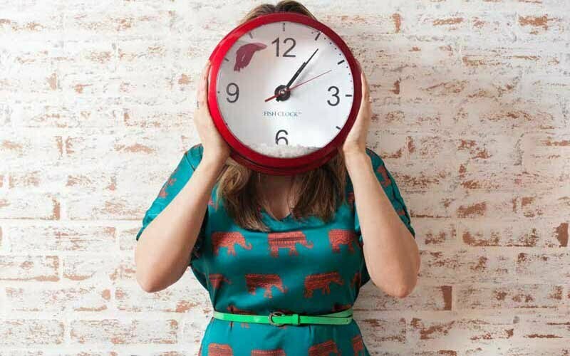 Frau hält große Uhr vor Gesicht