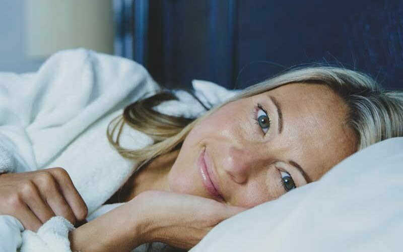 Lächelnde Frau liegt im Bett