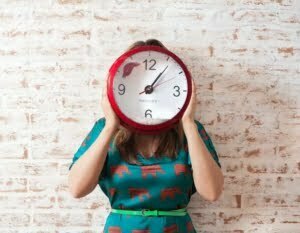 Frau hält große Uhr